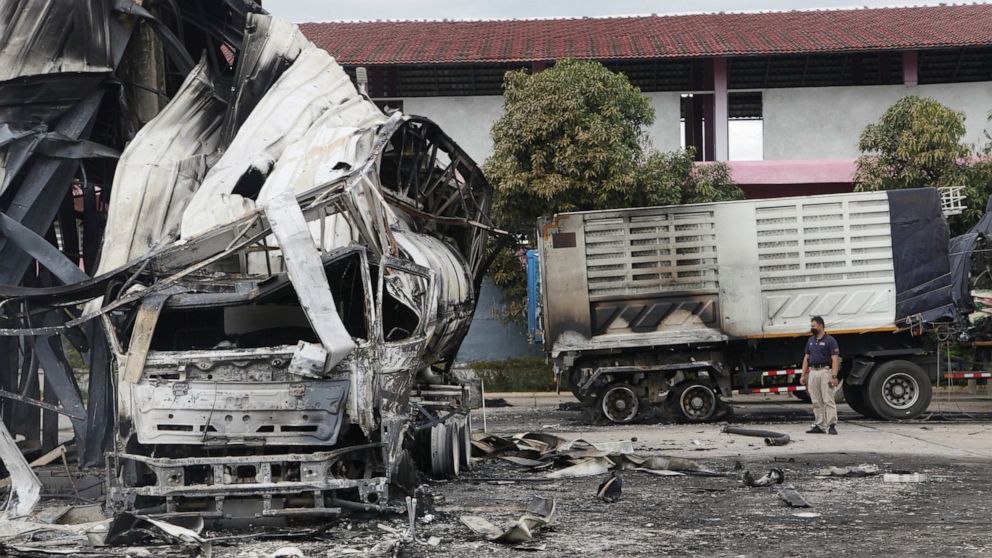A Thai officer stands beside the burnt down oil tanker at a gas station in Pattani province, southern Thailand, Wednesday, Aug. 17, 2022. A wave of arson and bombing attacks overnight hit Thailand’s southernmost provinces, which for almost two decade