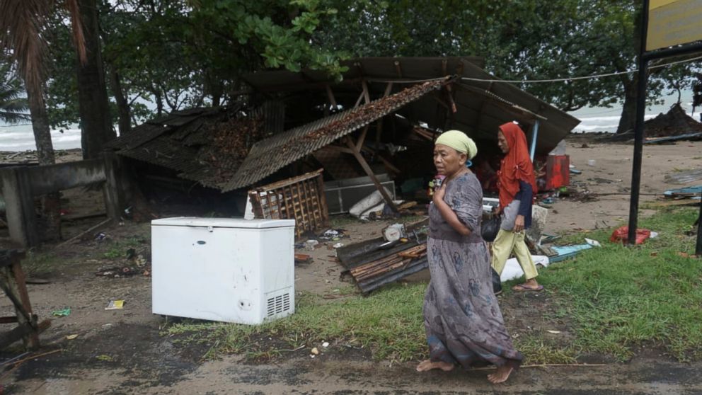 Residents walk past a house damaged by a tsunami, in Carita, Indonesia, Sunday, Dec. 23, 2018. The tsunami apparently caused by the eruption of an island volcano killed a number of people around Indonesia's Sunda Strait, sending a wall of water crash