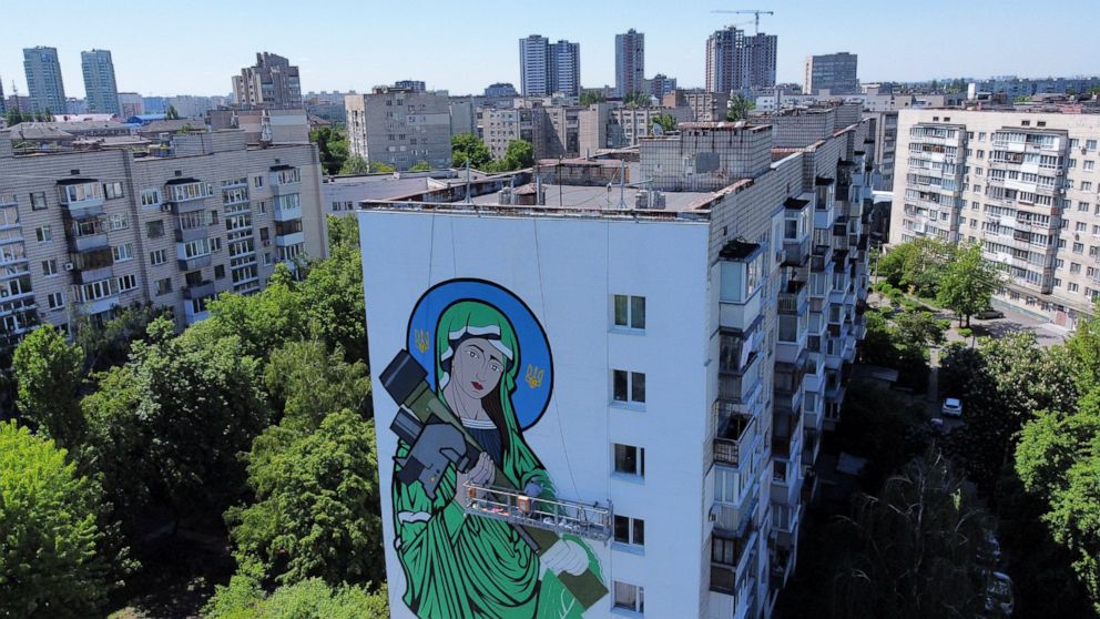 A worker paints a "Saint Javelin", a Virgin Mary holding an American-made anti-tank missile, in Kyiv, Ukraine, Tuesday, May 24, 2022. No matter where they live, the 3-month-old war never seems to be far away for Ukrainians. Those in towns and village