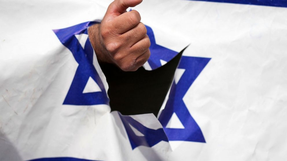 A demonstrator clenches his fist through a torn up representation of the Israeli flag in the annual pro-Palestinian Al-Quds, or Jerusalem, Day rally in Tehran, Iran, Friday, April 29, 2022. Iran does not recognize Israel and supports Hamas and Hezbol