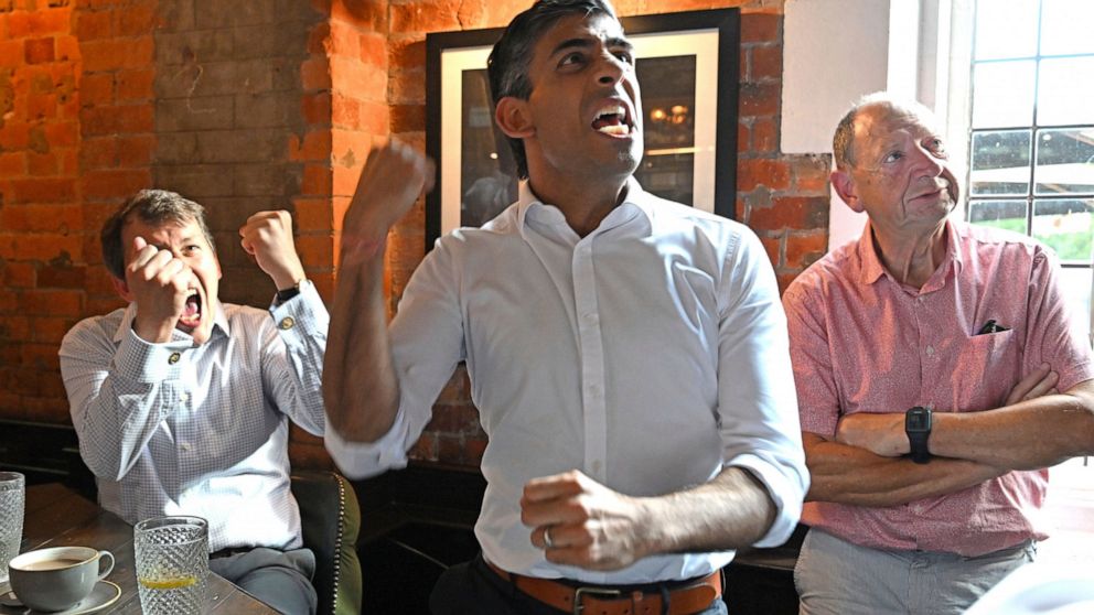 Rishi Sunak in Salisbury with MP John Glen, left, celebrates England's first goal while watching a screening of the UEFA Women's Euro 2022 final held at Wembley Stadium, Sunday July 31, 2022. (Finnbarr Webster/PA via AP)