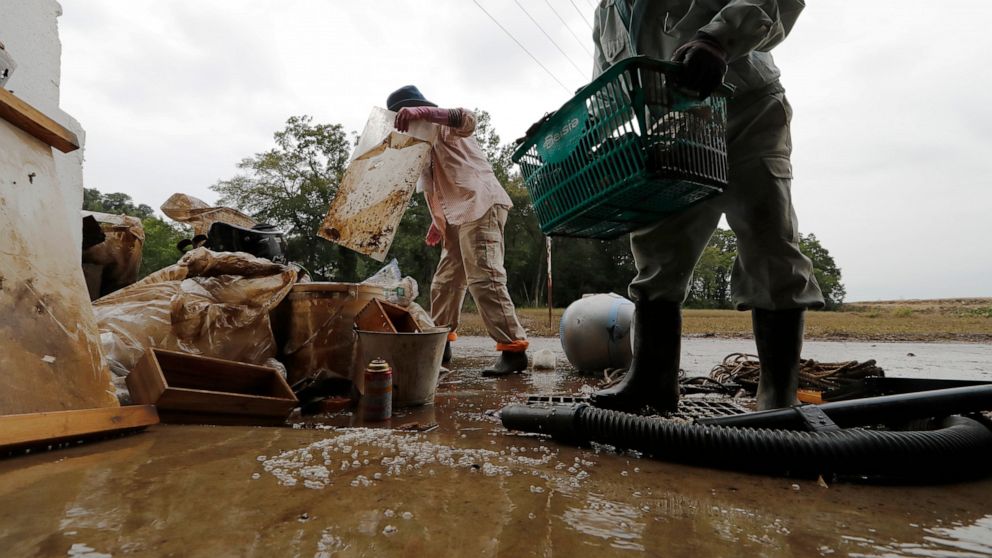 Residents Kazuo Saito, right, and Sumiko Saito clean up their home Monday, Oct. 14, 2019, in Kawagoe City, Japan. Typhoon Hagibis dropped record amounts of rain for a period in some spots, according to meteorological officials, causing more than 20 r