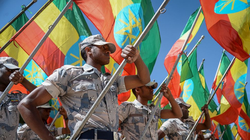 FILE - Members of the Ethiopian National Defense Force hold national flags as they parade during a ceremony to remember those soldiers who died on the first day of the Tigray conflict, outside the city administration office in Addis Ababa, Ethiopia, 