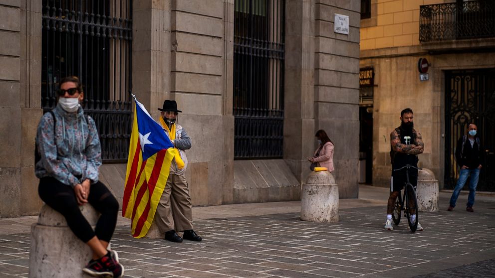 A man holding an "estelada" or independence flag waits for a protest to condemn a police raid on Catalan separatists in Barcelona, Spain, Wednesday, Oct. 28, 2020. Spanish officials say that police have arrested 21 individuals with links to the Catal