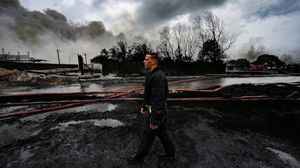 A firefighter walks on the site of a deadly fire at a large oil storage facility in Matanzas, Cuba, Tuesday, Aug. 9, 2022. The fire was triggered when lighting struck one of the facility's eight tanks late Friday, Aug. 5th. (Yamil Lage, Pool photo via AP)