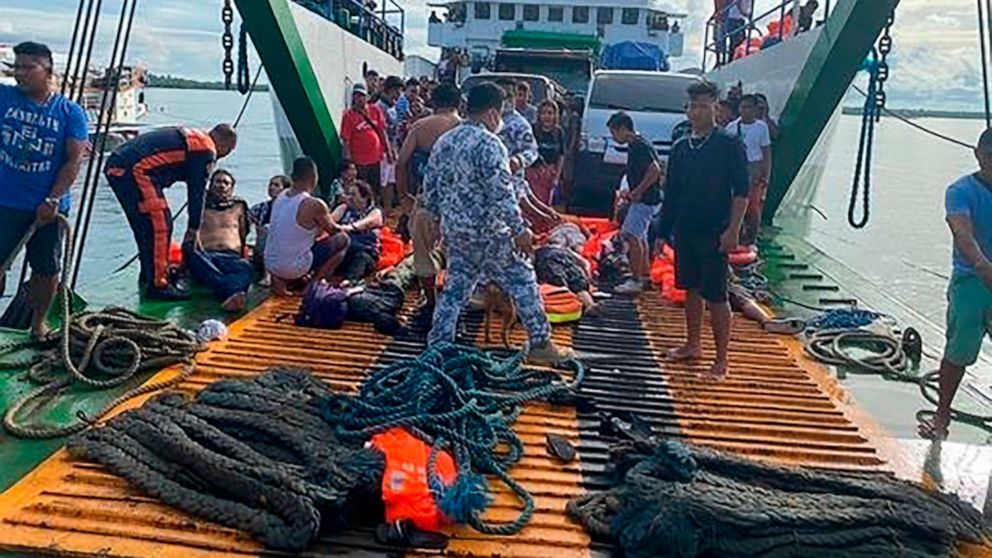 In this photo provided by the Philippine Coast Guard, passengers are checked after being rescued at the port of Real, Quezon province, Philippines Monday, May 23, 2022. A passenger ship caught fire as it nears their port of destination in Real town k