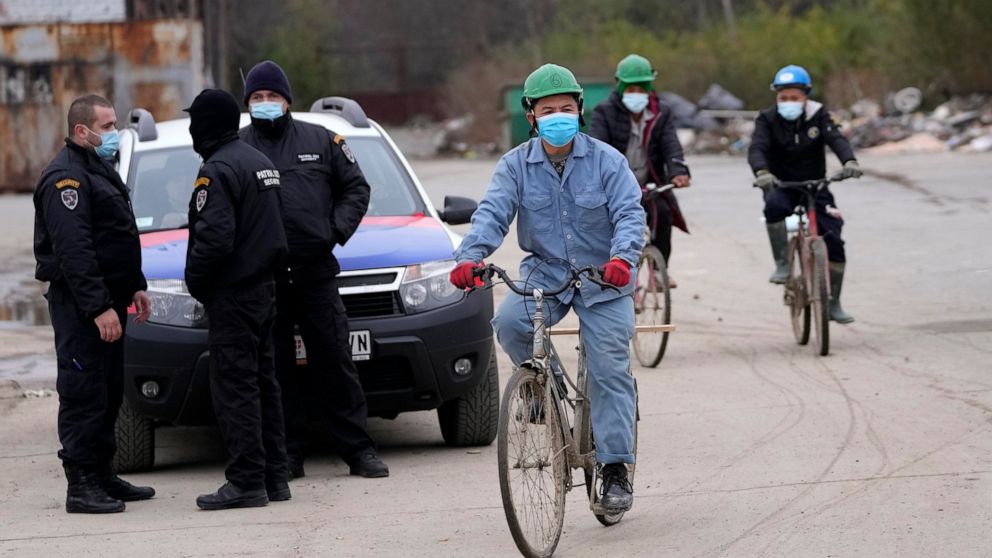 Vietnamese workers who are helping construct the first Chinese car tire factory in Europe ride bicycles past security officers near the northern Serbian town of Zrenjanin, 50 kilometers north of Belgrade, Serbia, Thursday, Nov. 18, 2021. Reports have