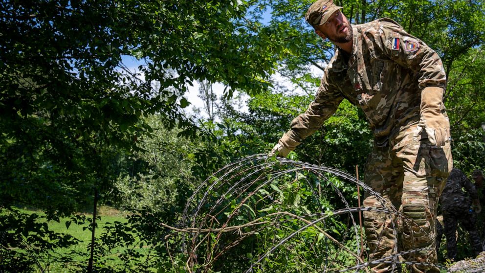 A Slovenian soldier deployed for the removal of border fence removes razor wire at the border crossing with Croatia in Krmacina, Slovenia, Friday, July 15, 2022. Slovenian army has started to remove the razor wire fence on the border with Croatia tha