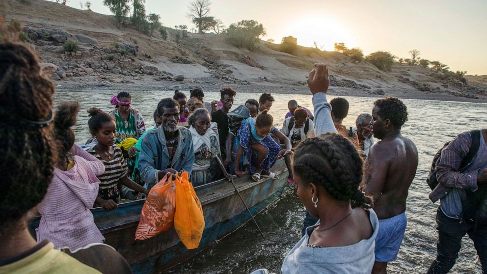 FILE - Tigrayan refugees arrive on the banks of the Tekeze River on the Sudan-Ethiopia border in Hamdayet, eastern Sudan on Dec. 2, 2020. A year after war began there, the findings of the only human rights investigation allowed in Ethiopia's blockade