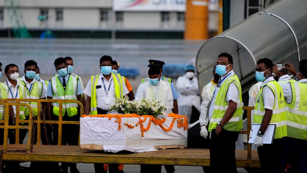 Sri Lankan air port workers stand next to a casket carrying remains of Priyantha Kumara, a Sri Lankan employee who was lynched by a Muslim mob in Sialkot last week after unloading it from an aircraft in Colombo, Sri Lanka, Monday, Dec. 6, 2021. (AP P