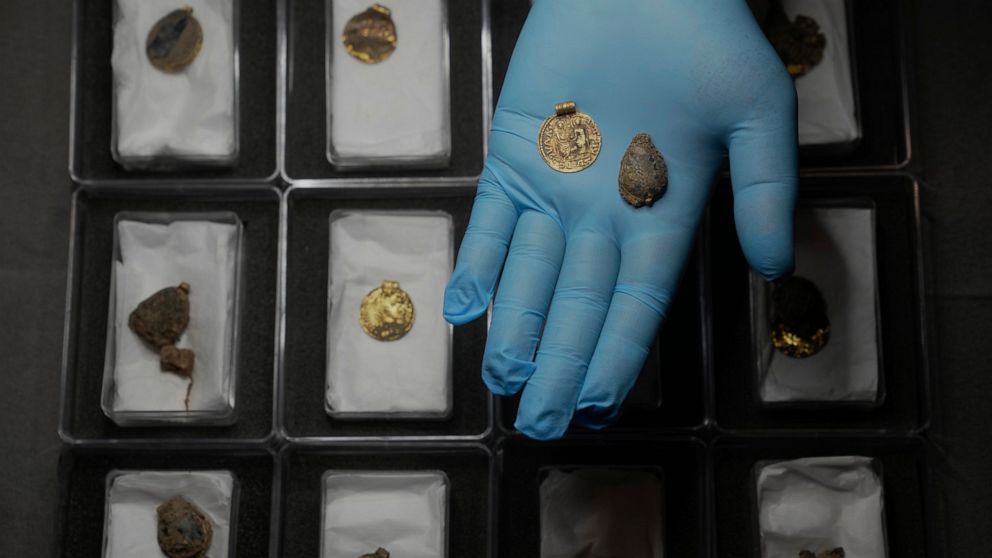 Liz Barham, senior conservator of the Museum of London Archaeology, displays an early medieval gold and gemstone necklace during a photo call, in London, Tuesday, Dec. 6, 2022. Archaeologists say a 1,300-year-old gold and gemstone necklace found duri