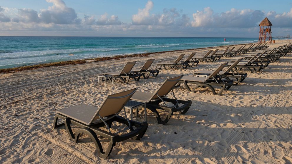 FILE - In this June 11, 2020 file photo, lounge chairs fill an empty beach in Cancun, Mexico. In a bill approved unanimously Tuesday, Sept. 30, 2020, Mexico’s Senate has voted to levy fines of up to $47,000 against hotels, restaurants or other proper