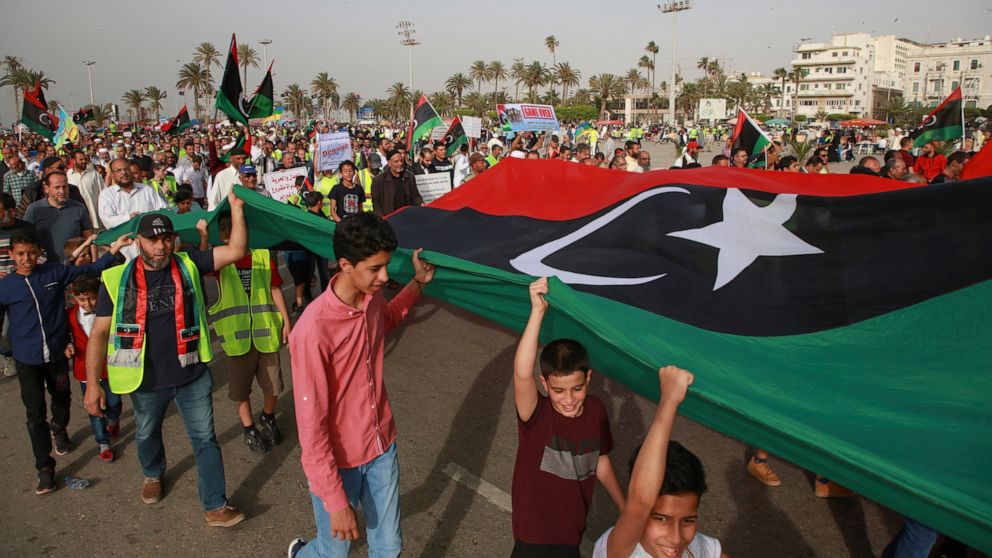 FILE - In this May 3, 2019 file photo, Libyans hold a demonstration against military operations by forces loyal to Field Marshal Khalifa Hifter, at Martyrs' Square in Tripoli, Libya. Two Libyan militia commanders and a Syrian war monitor group say Tu
