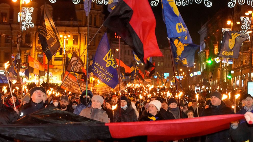 Activists of various nationalist parties carry torches during a rally in Kyiv, Ukraine, Saturday, Jan. 1, 2022. The rally was organized to mark the birth anniversary of Stepan Bandera, founder of a rebel army that fought against the Soviet regime and