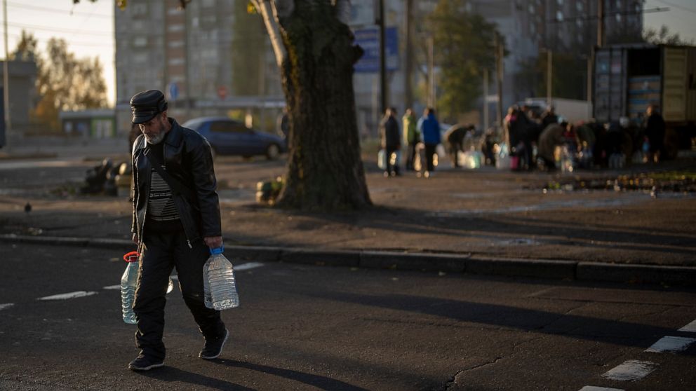 A man carries plastic bottles after refilling them in a tank, in the center of Mykolaiv, Monday, Oct. 24, 2022. Since mid-April, citizens of Mykolaiv, with a pre-war population of half a million people, have lived without a centralized drinking water