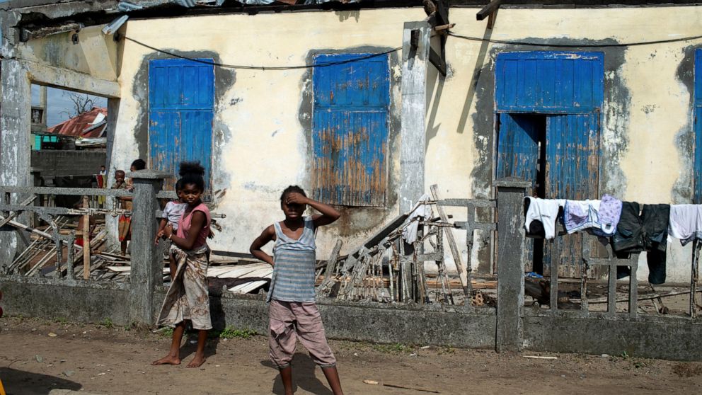 FILE — People stand outside a ruined home in Mananjary, Madagascar Thursday, Feb. 10, 2022. Even as southern African nations assess the devastation caused earlier this month by Cyclone Batsirai, a new tropical storm is approaching as the Indian Ocean