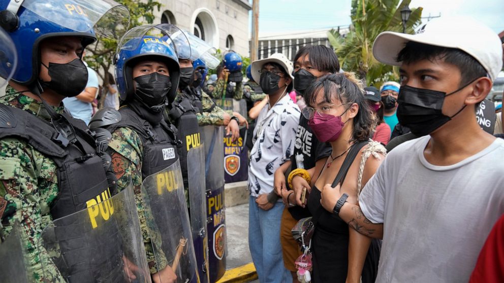 Students and activists face riot police during a rally in front of the office of the Commission on Elections as they question the results of the presidential elections in Manila, Philippines on Tuesday May 10, 2022. The namesake son of late Philippin
