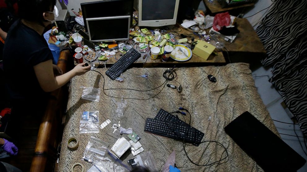 FILE - In this April 20, 2017, file photo, members of the National Bureau of Investigation and FBI gather evidence at the home of an American suspected child webcam cybersex operator during a raid in Mabalacat, Philippines. The Philippines has emerge