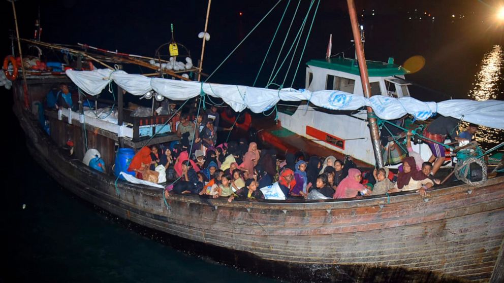 Rohingya refugees sit in a wooden boat as it arrives at Krueng Geukueh Port in North Aceh, Indonesia, Thursday, Dec. 30, 2021. An Indonesian navy ship towed the boat carrying 120 Rohingya Muslims into the port after it had drifted for days off the co