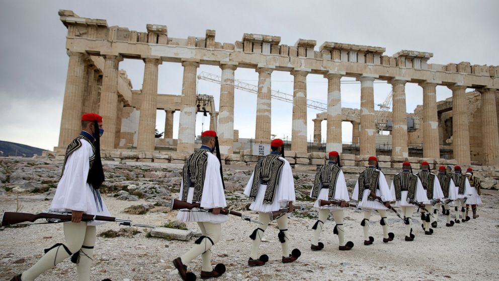Members of the Presidential Guard walk in front of the Parthenon temple atop of Acropolis Hill before the Greek flag raising ceremony in Athens, Thursday, March 25, 2021. Greece celebrates the bicentenary of the start of the country's war of independ