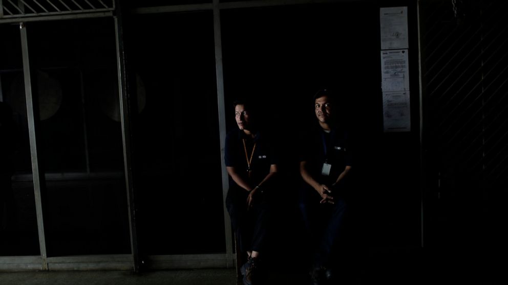People wearing El Universal newspaper uniforms sit inside a darkened office building during a power outage in Caracas, Venezuela, Monday, March 25, 2019. The subway suspended service because of the power cuts Monday, as local media reported outages i