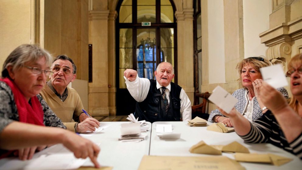 FILE - Volunteers talk as they count ballots papers after the first round of the French presidential election in Lyon, central France, Sunday, April 23, 2017. When France votes for president this weekend, voters will use the same system tried and tes