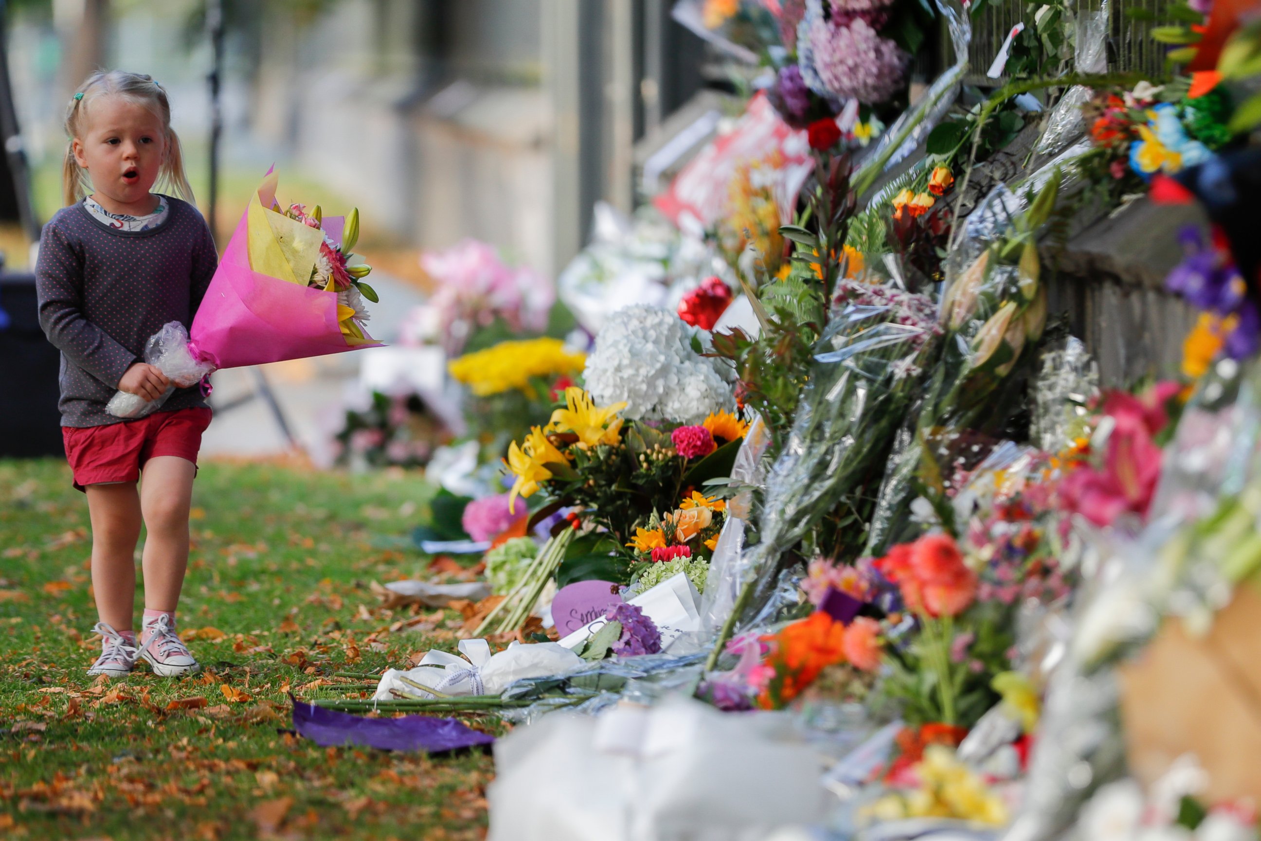 A girl walk to lay flowers on a wall at the Botanical Gardens in Christchurch, New Zealand, Sunday, March 17, 2019. New Zealand's stricken residents reached out to Muslims in their neighborhoods and around the country on Saturday, in a fierce determi