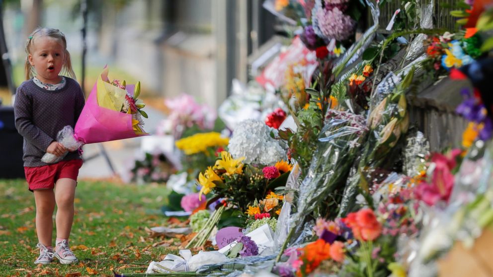 A girl walk to lay flowers on a wall at the Botanical Gardens in Christchurch, New Zealand, Sunday, March 17, 2019. New Zealand's stricken residents reached out to Muslims in their neighborhoods and around the country on Saturday, in a fierce determi