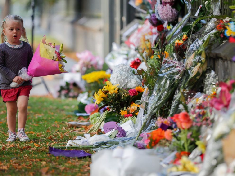A girl walk to lay flowers on a wall at the Botanical Gardens in Christchurch, New Zealand, Sunday, March 17, 2019. New Zealands stricken residents reached out to Muslims in their neighborhoods and around the country on Saturday, in a fierce determi