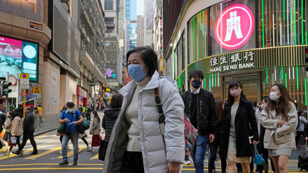People walk across a street in Hong Kong, Tuesday, Jan. 11, 2022. In an effort to limit omicron outbreaks, Hong Kong is closing kindergartens and primary schools after infections were reported in students, city leader Carrie Lam said Tuesday. Schools