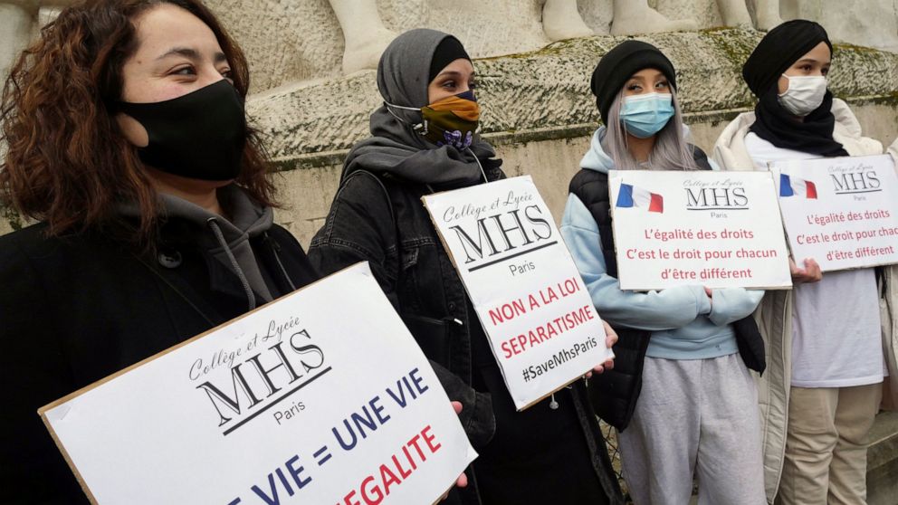 Activists hold placards reading « No to the separatism law » in the center, and « Equality of rights is the right of everyone to be different » on the right, during a gathering in Paris, Sunday, Feb. 14, 2021. Activists rallied Sunday in Paris to dem