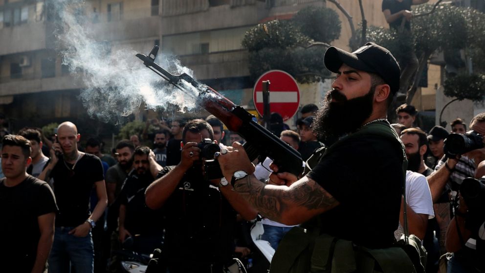 A supporter of the Shiite Amal group fires in the air during the funeral processions of Hassan Jamil Nehmeh, who was killed during Thursday clashes, in the southern Beirut suburb of Dahiyeh, Lebanon, Friday, Oct. 15, 2021. Dozens of gunmen opened fir