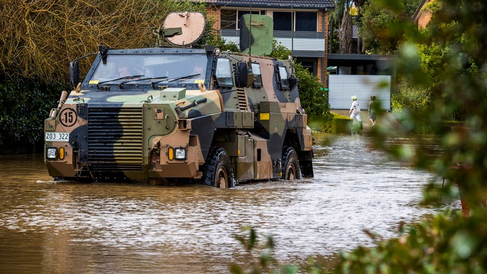 An Australian Army Bushmaster Protected Mobility Vehicle drives through a flooded street in McGrath Hills on the outskirts of Sydney, Monday, July 4, 2022. More than 50,000 residents of Sydney and its surrounds have been told to evacuate or prepare t