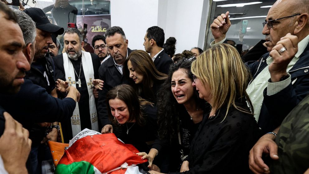 FILE - Colleagues and friends react as the Palestinian flag-draped body of veteran Al-Jazeera journalist Shireen Abu Akleh is brought to the news channel's office in the West Bank city of Ramallah, May 11, 2022. Israel's decision to absolve itself of