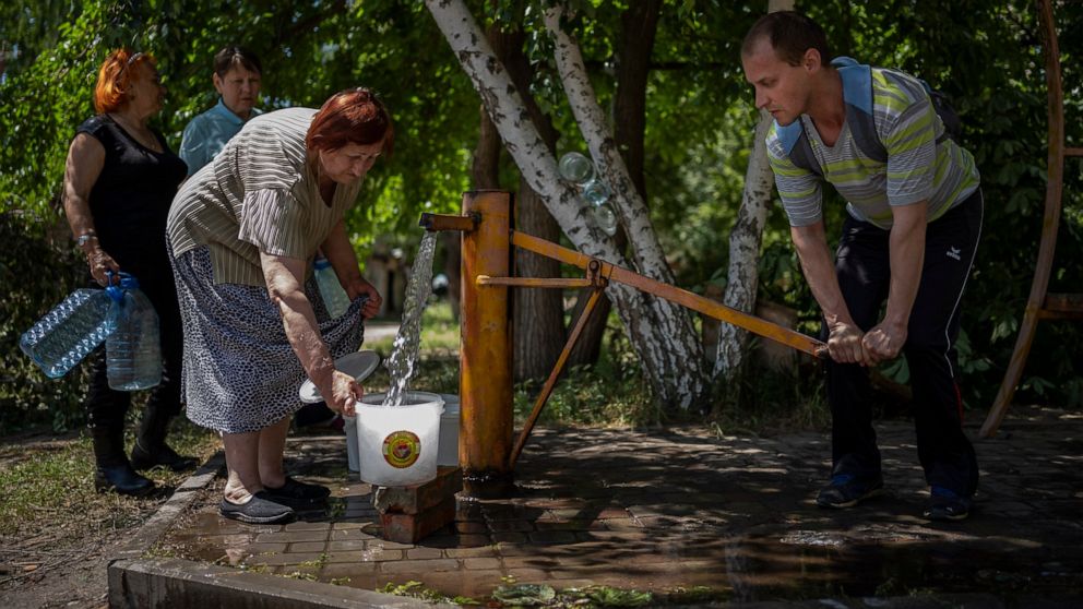 Residents gather to collect water from a pump in the street in Sloviansk, Ukraine, on Thursday, June 2, 2022. In towns and cities near the fighting in eastern Ukraine, artillery and missile strikes have downed power lines and punched through water pi