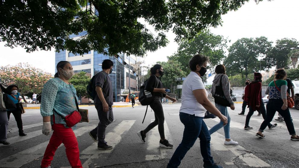 Pedestrians wear face masks amid the new coronavirus pandemic in Caracas, Venezuela, Monday, June 1, 2020. After two and a half months of COVID-19 related quarantine, some industries are allowed to reactivate under a scheme of five days' work and 10 