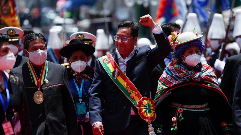 Bolivia's new President Luis Arce, center, raises his fist as he walks with Vice President David Choquehuanca, left, on their inauguration day in La Paz, Bolivia, Sunday, Nov. 8, 2020. (AP Photo/Juan Karita)