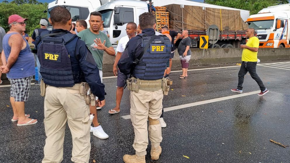 Truck drivers talk with police on the Rio de Janeiro-Sao Paulo highway as drivers park their cargo to protest the previous day’s election defeat of President Jair Bolsonaro, in Barra Mansa, Rio de Janeiro state, Brazil, Monday, Oct. 31, 2022. (AP Pho
