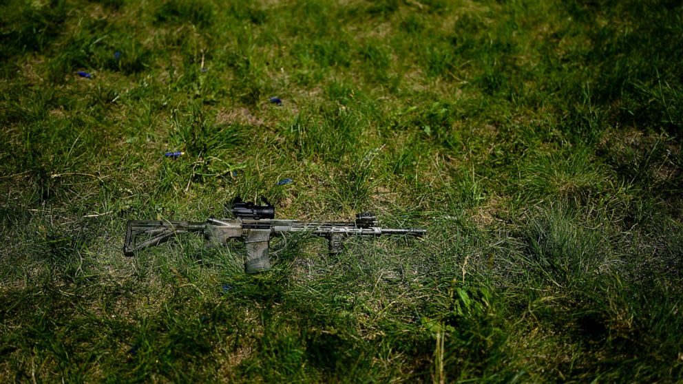 A rifle is seen on the grass as civilian militia men train at a shooting range in outskirts Kyiv, Ukraine, Tuesday, June 7, 2022. (AP Photo/Natacha Pisarenko)