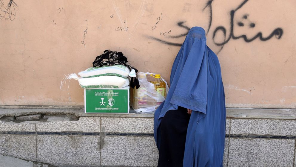 An Afghan woman receives free food donated by King Salman Humanitarian Aid and Relief Center, ahead of the upcoming holy fasting month of Ramadan in Kabul, Afghanistan, Sunday, May 5, 2019. Muslims throughout the world celebrate the holy fasting mont