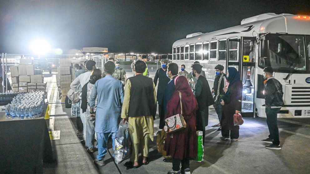 In this image provided by the U.S. Air Force, a group of Afghan evacuees depart a bus at Ramstein Air Base, Germany, Friday, Aug. 20, 2021. Ramstein Air Base is providing safe, temporary lodging for qualified evacuees from Afghanistan as part of Oper
