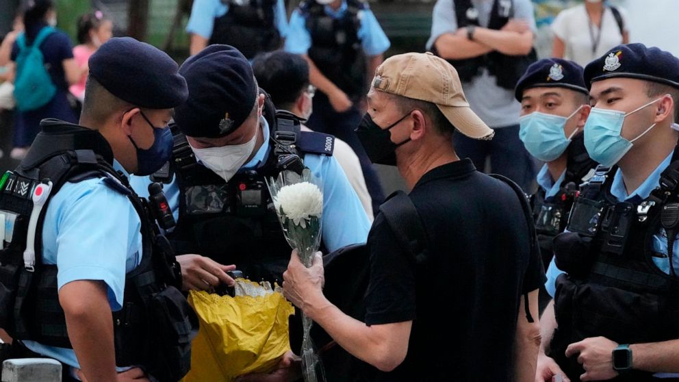 Police officers stop and search a man holding a flower at the Hong Kong's Victoria Park, Saturday, June 4, 2022. Dozens of police officers patrolled Hong Kong's Victoria Park on Saturday after authorities for a second consecutive third banned public 