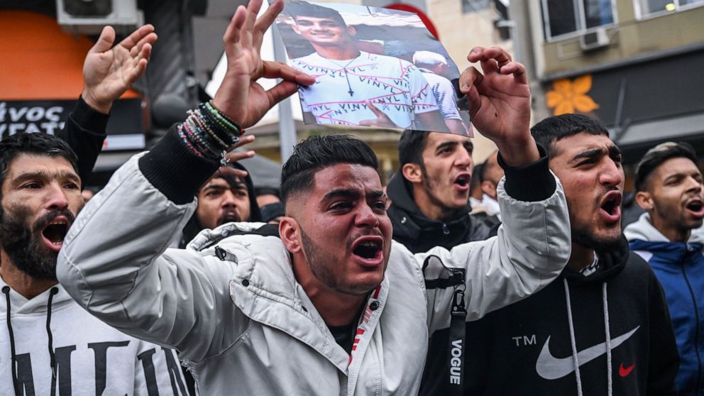 Relatives and other protesters from the Roma community chant slogans outside the courthouse in Greece's second largest city of Thessaloniki, holding up photos of an injured 16-year-old and calling for justice, on Friday, Dec. 9, 2022. A Greek police 