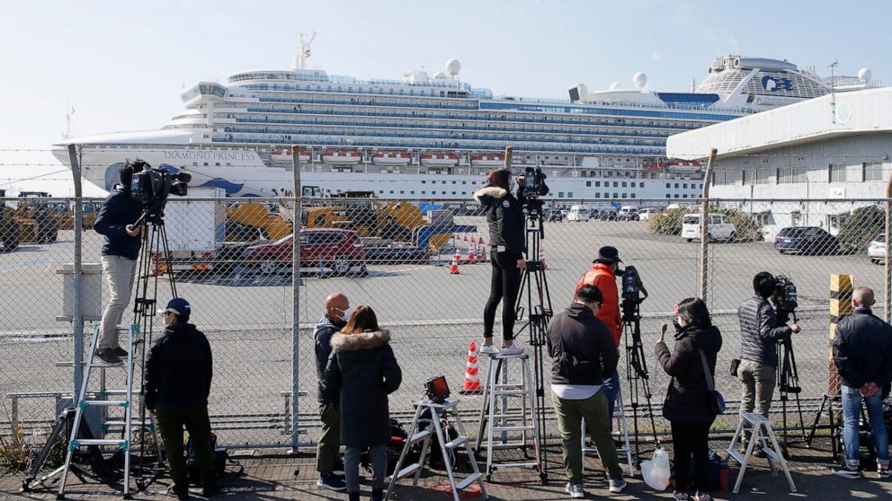 Journalists gather to film the quarantined ship Diamond Princess, background, at Yokohama port in Yokohama, near Tokyo Monday, Feb. 17, 2020. Japanese officials have confirmed 99 more people infected by the new virus aboard the ship, the Health Minis