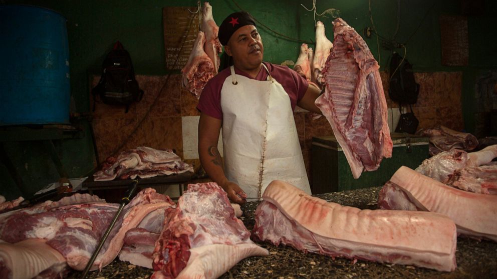 A meat vendor sells pork at a private market in Havana, Cuba, Friday, Dec. 23, 2022. (AP Photo/Ismael Francisco)