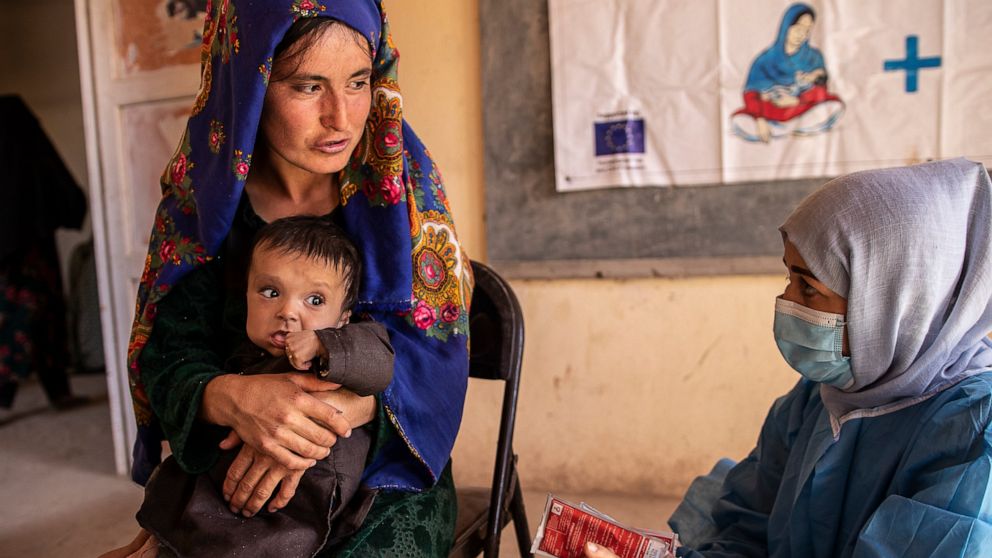 A Save the Children nutrition counsellor, right, explains to Nelab, 22, how to feed her 11-month-old daughter, Parsto, with therapeutic food, which is used to treat severe acute malnutrition, in Sar-e-Pul province of Afghanistan, Thursday, Sept. 29, 