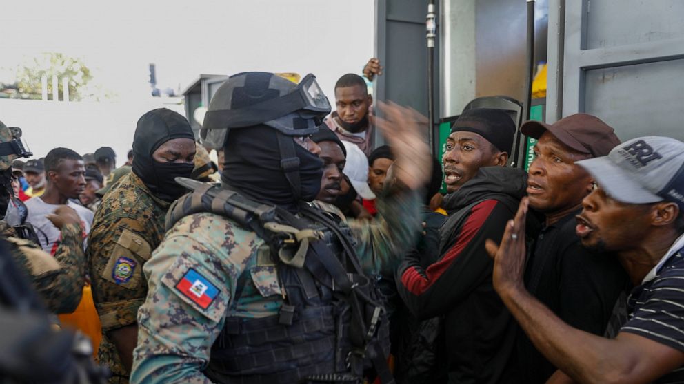 Police officers attempt to control a crowd gathered at a gas station hoping to fill their tanks, in Port-au-Prince, Haiti, Thursday, Nov. 4, 2021. (AP Photo/Odelyn Joseph)