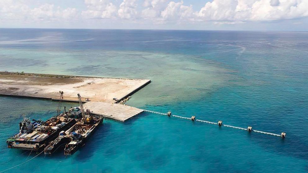 In this photo provided by the Department of National Defense, ships carrying construction materials are docked at the newly built beach ramp at the Philippine-claimed island of Thitu, in the disputed South China Sea, June 9, 2020. The Philippines has