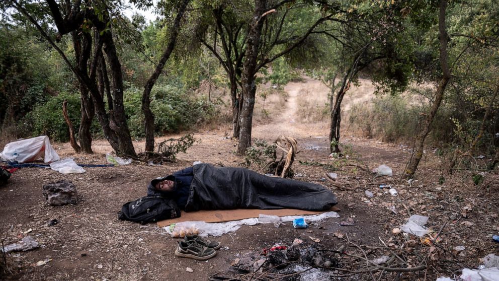 A Syrian migrant sleeps inside a forest near Ieropigi village, northern Greece, at the Greek - Albanian border, on Tuesday, Sept. 28, 2021. A relatively smooth section of Greece's rugged border with Albania is turning into a major thoroughfare north 