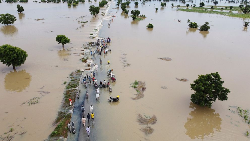 People walk through floodwaters after heavy rainfall in Hadeja, Nigeria, Monday, Sept 19, 2022. Nigeria is battling its worst floods in a decade with more than 300 people killed in 2021 including at least 20 this week, authorities told the Associated